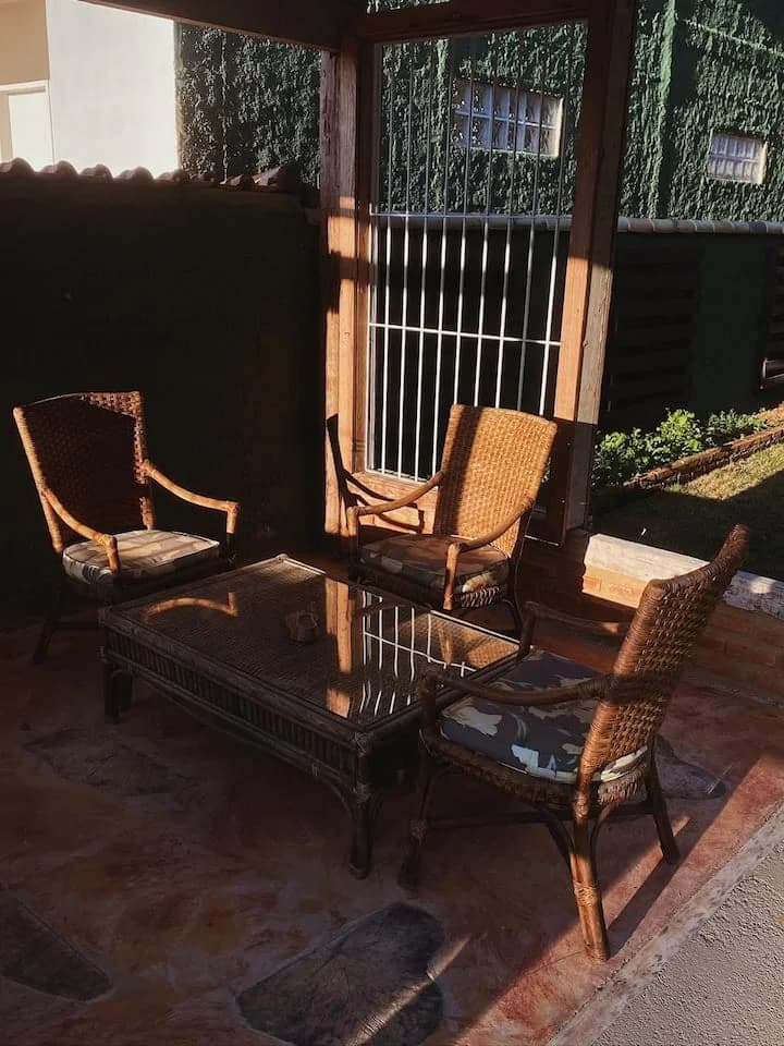 Canto de estar com poltronas de vime e mesa de centro, junto à parede tomada de hera