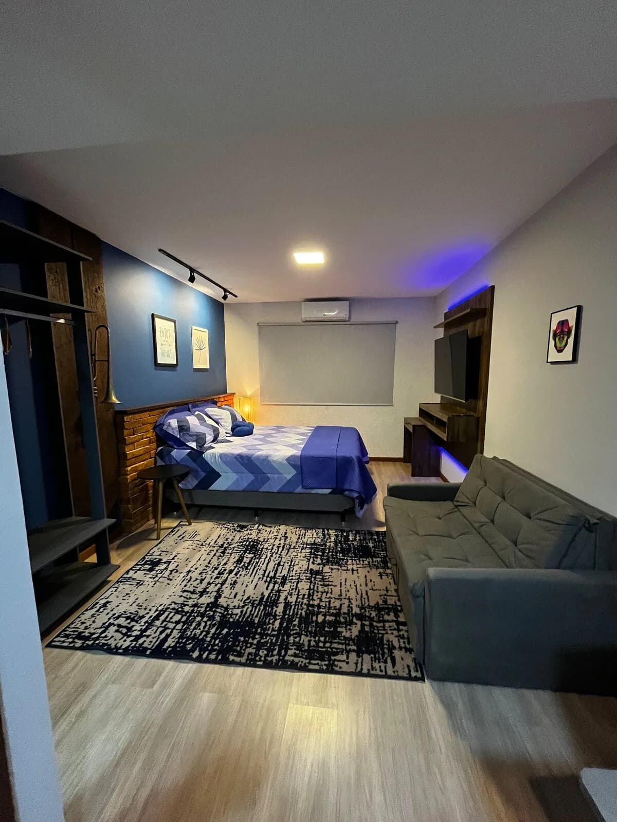 Loft Blue Jazz: Azul-noite com luz indireta, sofá de canto e mesa posta para dois.